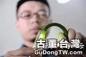 工作人員利用手機的手電燈光照著看產品內部結構，產品中有氣泡即可判定是玻璃。